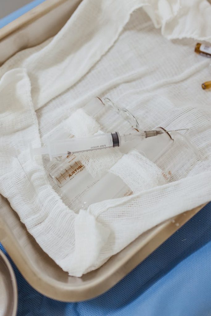 Close-up of a medical syringe placed on a sterile tray covered with gauze, in a clinical setting.