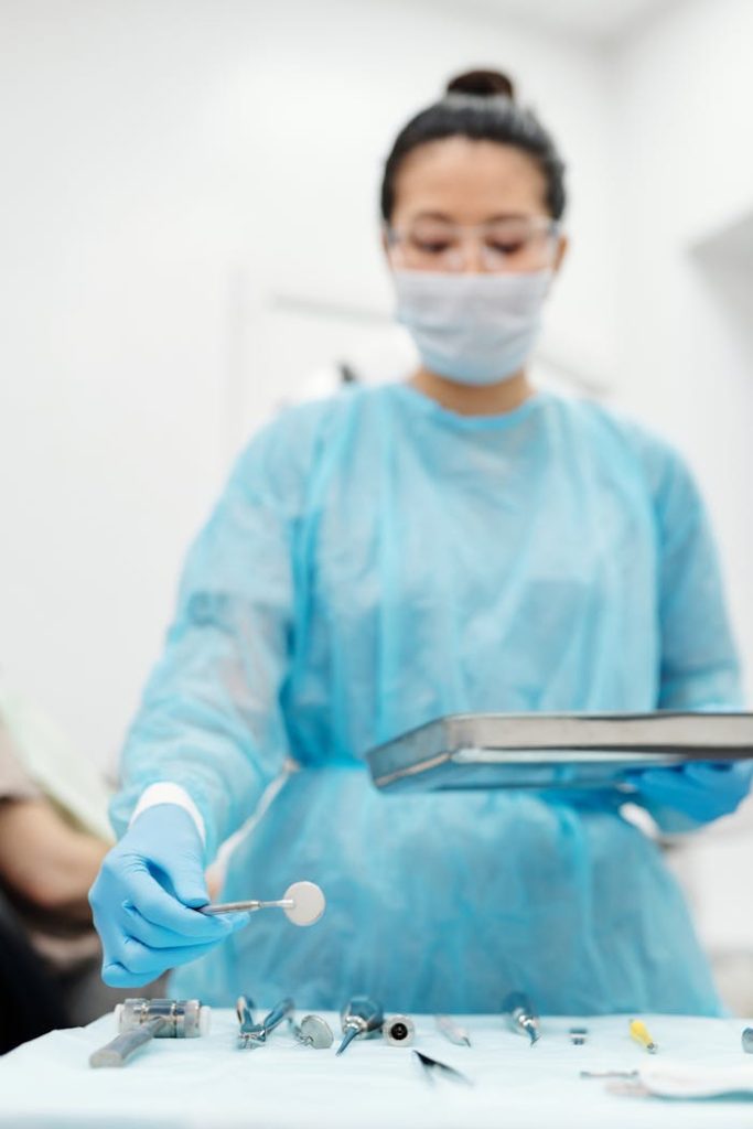 Dentist in protective gear arranging dental tools in a clinic for a procedure.